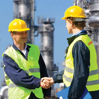 two-industry-workers-shaking-hands-outside-a-chemical-refinery