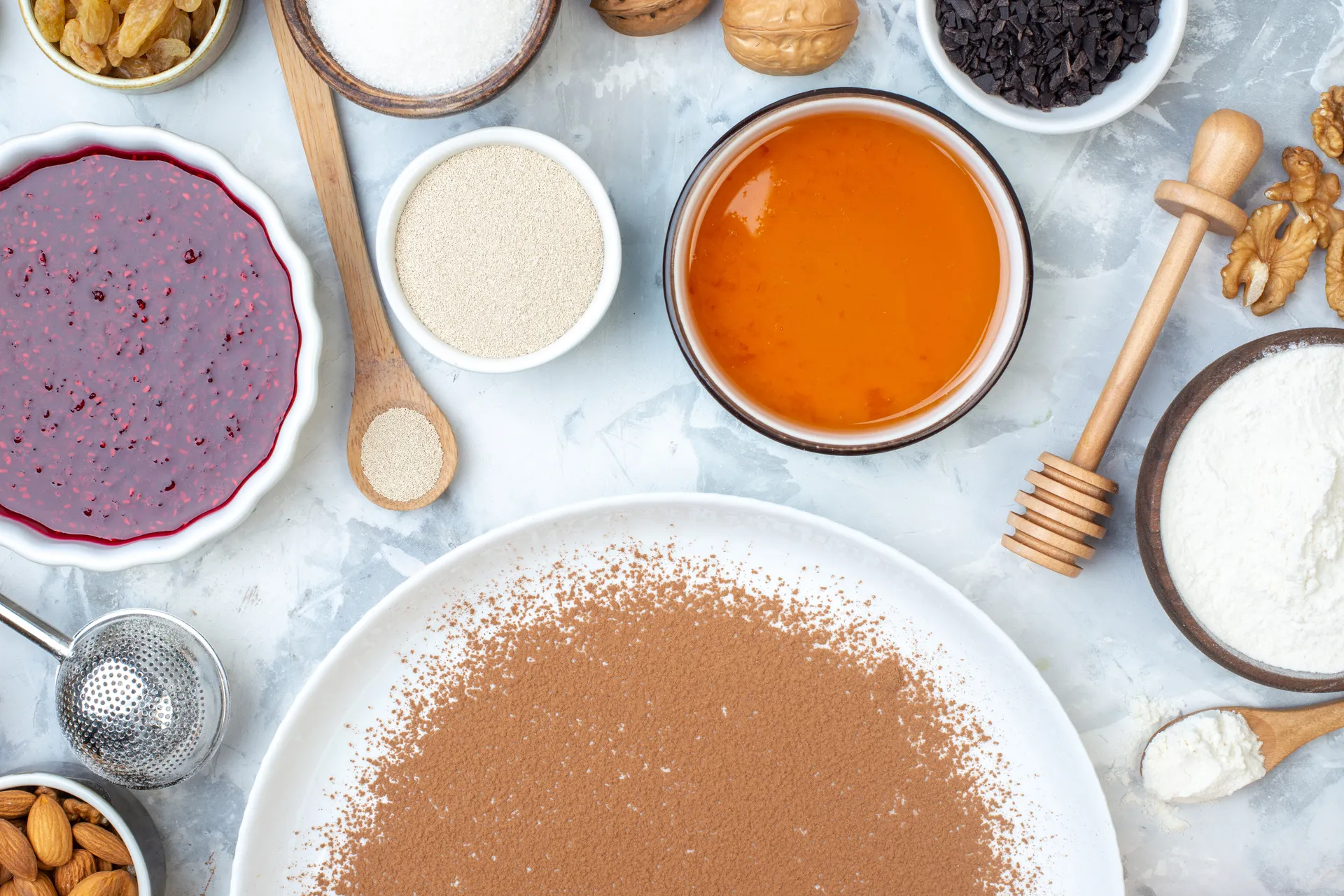 top-view-powdered-cocoa-round-plate-walnut-bowls-with-jam-honey-flour-wooden-spoon-honey-stick-table