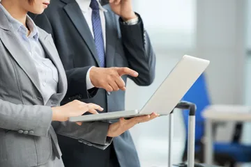 unrecognizable-man-woman-business-suits-looking-laptop-screen-together