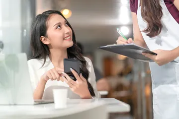 asian-female-customer-order-food-drink-from-smartphone-digital-menu-social-contactless-waitress-staff-smiling-millennial-waitress-with-paper-chart-taking-order-from-yo