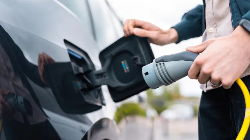 man-opening-cars-charge-socket-holding-charger-charge-station